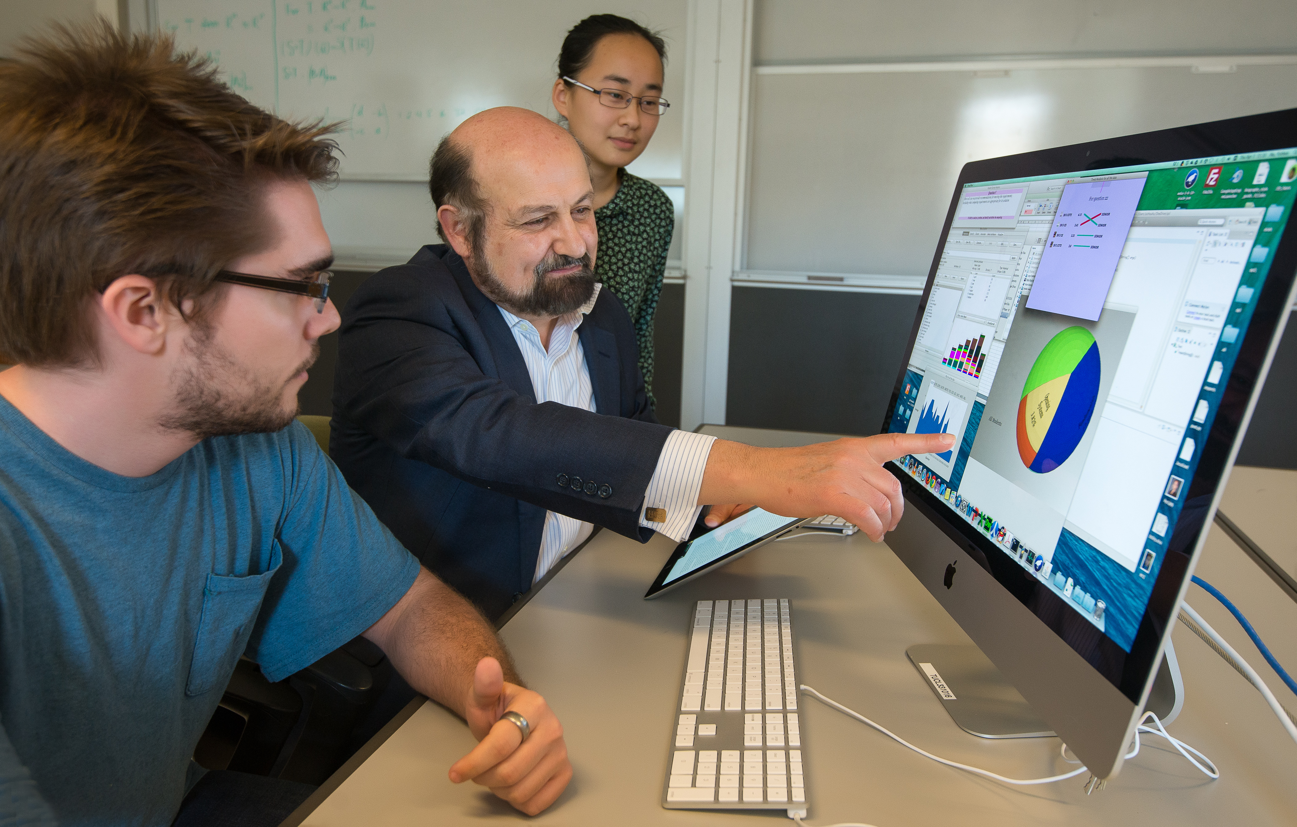 students and professor looking at a computer