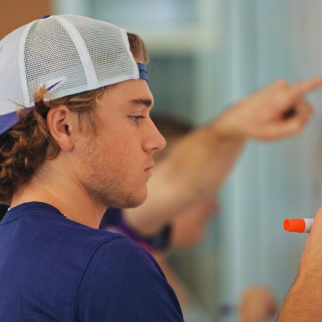 professor teaching students at a white board