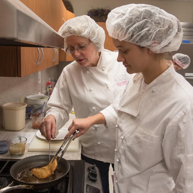 student working with a frying pan cooking food